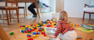 Ein zweijähriges Kind spielt im Wohnzimmer, während seine Mutter Zuhause im Homeoffice an einem Laptop arbeitet. Der Rückzug vom Arbeitsplatz ins Homeoffice soll ein zentraler Baustein im Kampf gegen die Corona-Pandemie werden. +++ dpa-Bildfunk +++