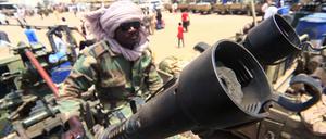 Ein Milizionär sitzt neben militärischer Ausrüstung, die angeblich während eines Gefechts im umkämpften Gebiet in Süd-Darfur erbeutet wurde. 