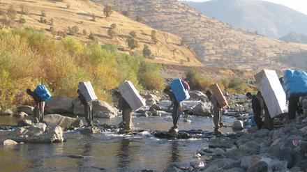 Schwere Last. Kurdische Lastenträger überqueren die Grenze durch einen Fluss in Richtung iranische Grenze. (Foto von Rahman Hassani/SOPA Images/LightRo)