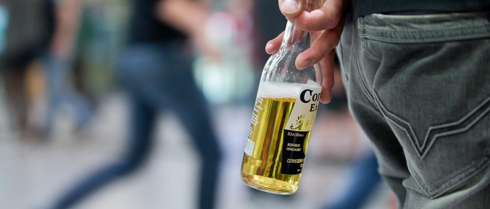 Ein Jugendlicher mit einer Flasche Bier in der Hand.