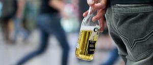 Ein Jugendlicher mit einer Flasche Bier in der Hand.