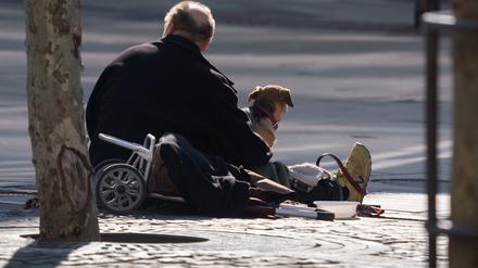 Ein Mann sitzt mit seinem Hund an der Straße und wartet auf Gaben von Passanten (Archivbild).