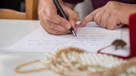 Eine Hand hält einen Füller, darunter ein Schriftstück.