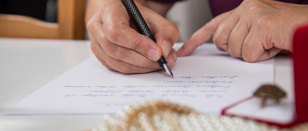 Eine Hand hält einen Füller, darunter ein Schriftstück.