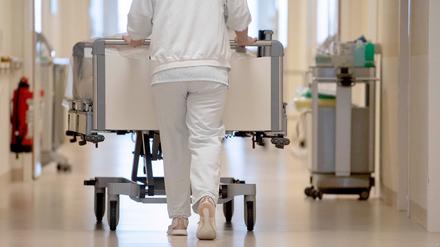 Eine Krankenpflegerin schiebt ein Krankenbett durch einen Flur.
