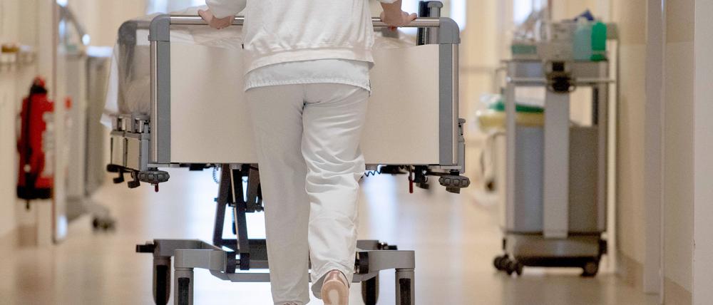 Eine Krankenpflegerin schiebt ein Krankenbett durch einen Flur. (Symbolbild)