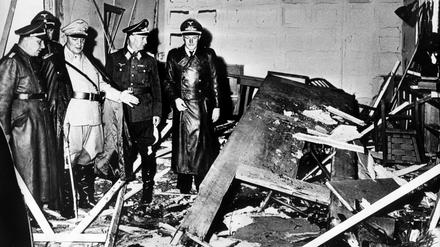 Reichsmarschall Hermann Göring (helle Uniform) und der Chef der „Kanzlei des Führers“, Martin Bormann (l.), begutachten die Zerstörung im Raum der Karten-Baracke im Führerhauptquartier Rastenburg, wo Oberst Stauffenberg am 20. Juli 1944 eine Sprengladung zündete, mit der Absicht Hitler zu töten.