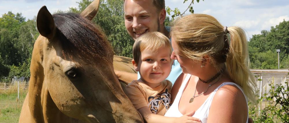 Cato mit seinen Eltern Christina und Dominic Schwandt. Die Familie sammelt Spenden, weil der gemeinsame Therapiehof durch die Erkrankung in finanzielle Schieflage geraten ist.