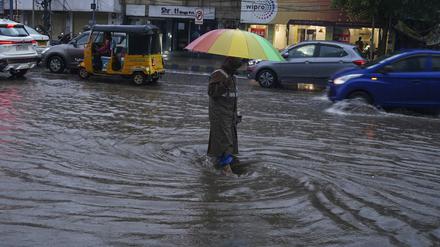 20.07.2023, Indien, Hyderabad: Ein Mann geht durch eine überflutete Straße. In Indien fällt der Monsunregen von Juni bis Oktober. Starke Regenfälle, die heftige Überflutungen und Erdrutsche auslösen, sind in der Monsunzeit in Südasien normal. Der Monsun dauert gewöhnlich von Juni bis September. Foto: Mahesh Kumar A./AP/dpa +++ dpa-Bildfunk +++