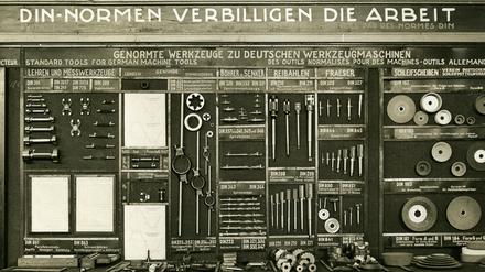 Präsentation von genormten Werkzeugen und dem Slogan „DIN Normen verbilligen die Arbeit“. Das Datum der Aufnahme ist nicht bekannt.