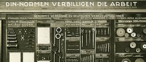 Präsentation von genormten Werkzeugen und dem Slogan „DIN Normen verbilligen die Arbeit“. Das Datum der Aufnahme ist nicht bekannt.