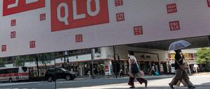 Pedestrians are reflected in a mirror outside a branch of the Fast Retailing clothing brand Uniqlo along a street in downtown Tokyo on July 10, 2023. (Photo by Richard A. Brooks / AFP)