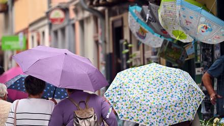 Touristen laufen mit Regenschirmen über die Erfurter Krämerbrücke. Reichlich Wolken und den einen oder anderen Regen- und Gewitterschauer erwartet der Deutsche Wetterdienst (DWD) für das kommende Wochenende. Auch zum Start in die neue Woche gibt es wechselhaftes Wetter. 