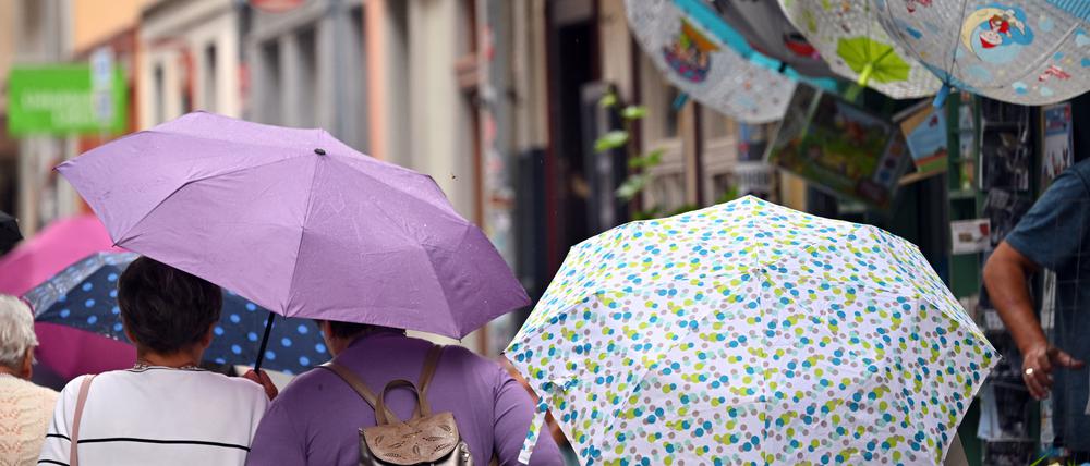 Touristen laufen mit Regenschirmen über die Erfurter Krämerbrücke. Reichlich Wolken und den einen oder anderen Regen- und Gewitterschauer erwartet der Deutsche Wetterdienst (DWD) für das kommende Wochenende. Auch zum Start in die neue Woche gibt es wechselhaftes Wetter.