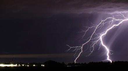 Ein Blitz zuckt bei einem Sommergewitter am nächtlichen Himmel.
