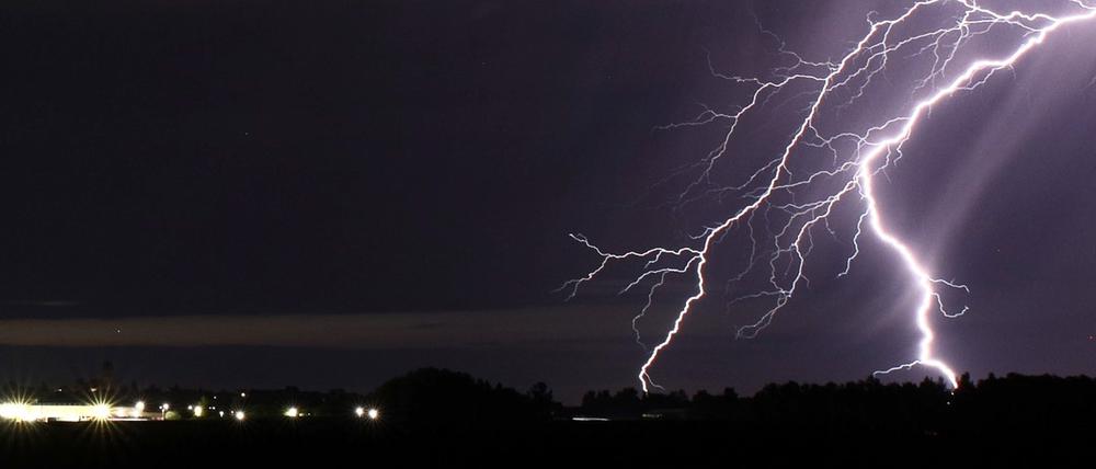 Ein Blitz zuckt bei einem Sommergewitter am nächtlichen Himmel.