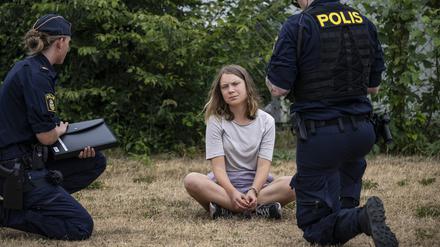 Zwei Polizeibeamte sprechen mit der Klimaaktivistin Greta Thunberg (Archivbild). 