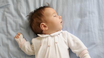 Newborn baby girl sleeping on blue sheets at home