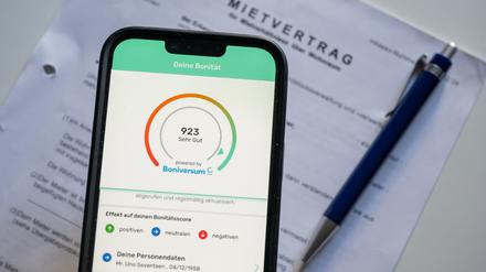 Ein Screenshot der App «Bonify» ist auf dem Bildschirm eines Mobiltelefon vor einem Mietvertrag zu sehen. In der von der Schufa vorgestellten Bonify-App zur Einsicht in die eigene Kreditwürdigkeit hat eine gravierende Sicherheitslücke geklafft. 