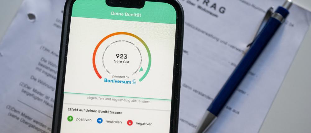 Ein Screenshot der App «Bonify» ist auf dem Bildschirm eines Mobiltelefon vor einem Mietvertrag zu sehen. In der von der Schufa vorgestellten Bonify-App zur Einsicht in die eigene Kreditwürdigkeit hat eine gravierende Sicherheitslücke geklafft. 