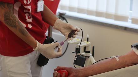 Eine Krankenpflegerin hält Geräte zur Blutspende in der Hand in einem Raum in einem Blutspendezentrum. 