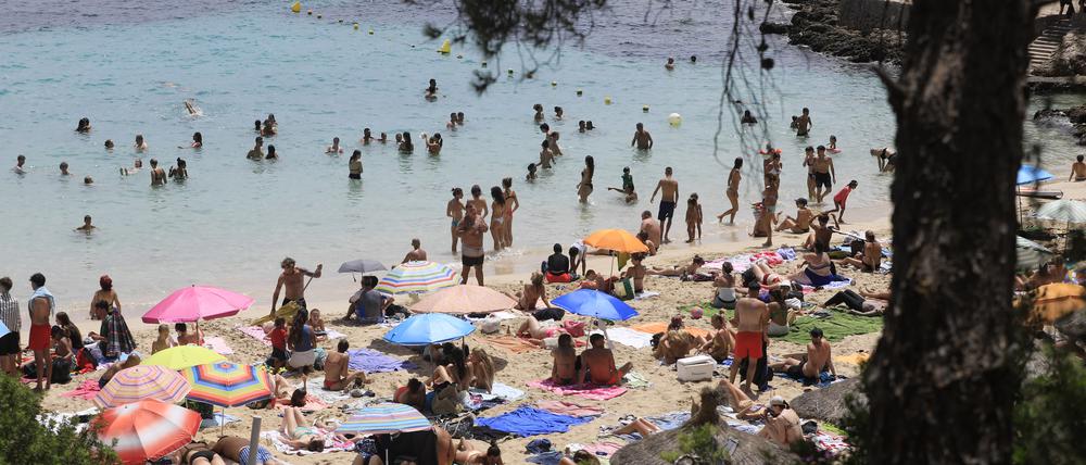 Menschen schwimmen und sonnen sich am Strand von Illetes auf Mallorca.