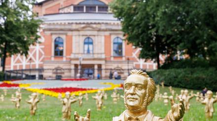 dpatopbilder - 25.07.2023, Bayern, Bayreuth: Goldfarbene Wagner-Figuren des Konzeptkünstler Ottmar Hörl stehen im Rahmen der Kunstinstallation «You're welcome» vor dem Festspielhaus vor Beginn der Bayreuther Festspiele. Die zahlreich aufgestellten Figuren sollen mit der Geste der Umarmung das Publikum der Festspiele willkommen heißen. Foto: Daniel Karmann/dpa - ACHTUNG: Nur zur redaktionellen Verwendung im Zusammenhang mit einer Berichterstattung über die Kunstaktion und nur mit vollständiger Nennung des vorstehenden Credits +++ dpa-Bildfunk +++