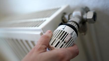 Eine Frau dreht an einem Heizungsthermostat.