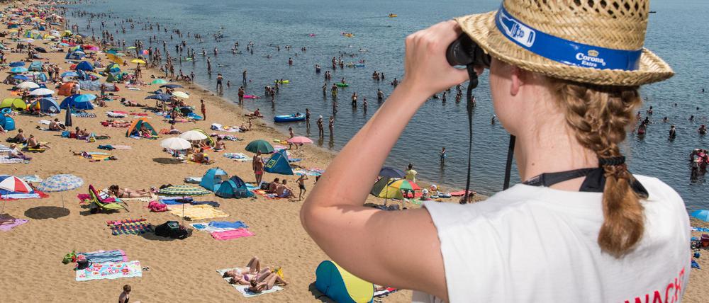 Die Rettungsschwimmerin Susi Voll von der Wasserwacht des DRK überwacht am 04.07.2015 den vollen Badestrand des Helenesees nahe Frankfurt (Oder) (Brandenburg). Foto: Patrick Pleul/dpa +++(c) dpa - Bildfunk+++