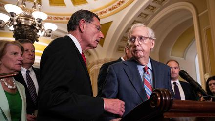 Der republikanische Senator John Barrasso reicht dem Minderheitsführer des Senats, Mitch McConnell, während einer Pressekonferenz hilfreich die Hand.