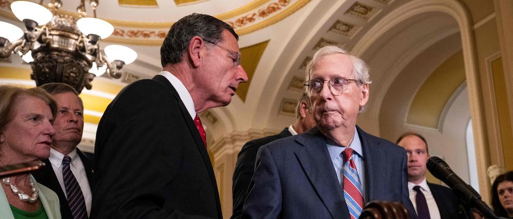 Der republikanische Senator John Barrasso reicht dem Minderheitsführer des Senats, Mitch McConnell, während einer Pressekonferenz hilfreich die Hand.