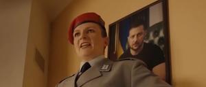 Eine Frau in Bundeswehruniform hängt ein Bild vom ukrainischen Präsidenten auf und ruft „Heil, Selenskyj!“