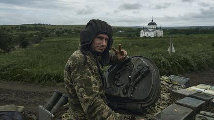 Ein ukrainischer Soldat zeigt ein Siegeszeichen auf einem Panzer an der Frontlinie. 
