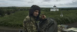 Ein ukrainischer Soldat zeigt ein Siegeszeichen auf einem Panzer an der Frontlinie.