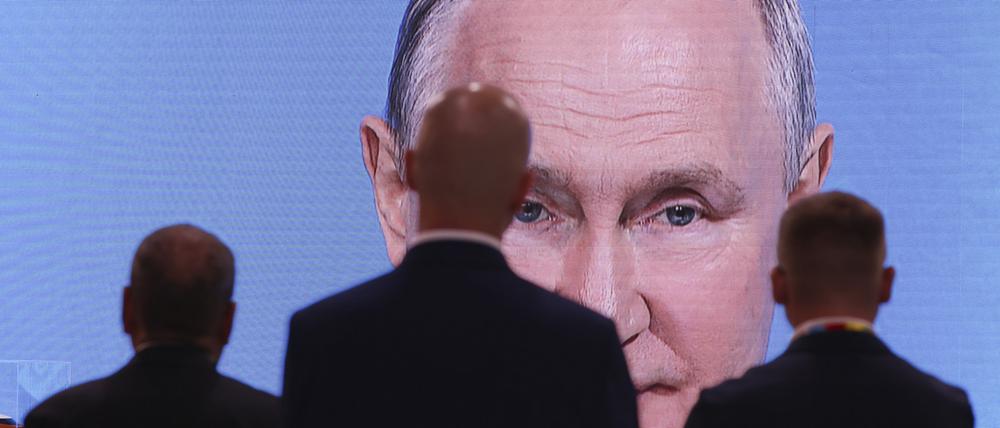 Männer schauen auf einen Bildschirm, der die Ansprache von Russlands Präsident Putin bei der Plenarsitzung des Russisch-Afrikanischen Wirtschafts- und Humanitären Forums überträgt.