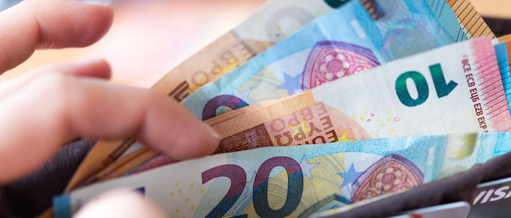 Eine Frau hält eine Geldbörse mit Banknoten in der Hand. 