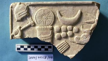 Stück der FU-Sammlung: ein reliefiertes Steinplattenfragment aus Tell Schech Hamad. Es zeigt den Wettergott Hadad (mit Hand und Kopfschmuck).
