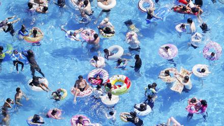 Ein Foto aus einem Hubschrauber zeigt Menschen mit Schwimmreifen in einem Schwimmbad. 