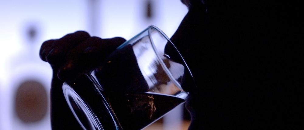 Ein Bar-Besucher trinkt ein Glas Whiskey mit Eis.
