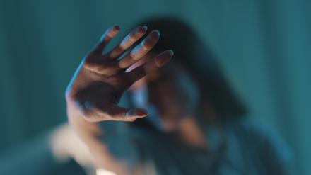 Eine Frau hält ihre Hand schützend ihr Gesicht.