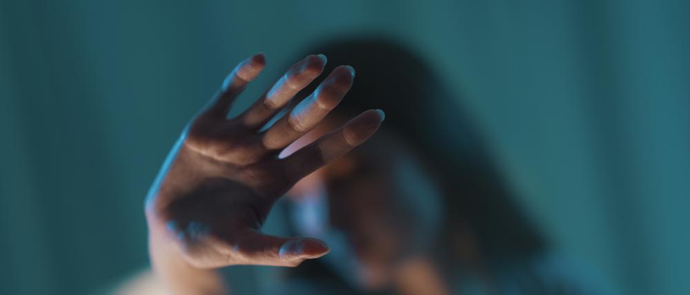 Eine Frau hält ihre Hand schützend ihr Gesicht.