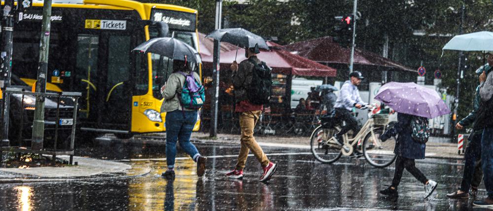 Menschen laufen mit Regenschirmen durch Berlin. (Symbolbild)