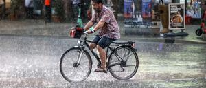 Ein Fahrradfahrer fährt bei strömendem Regen an der Potsdamer Straße, Berlin.