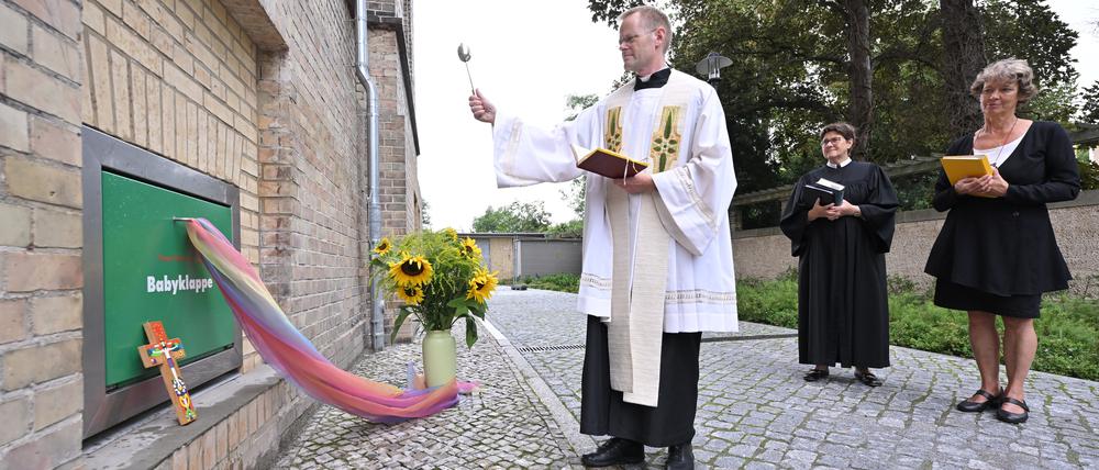 Propst Arnd Franke und die beiden Klinikseelsorgerinnen bei der Segnung der wieder in Betrieb genommenen Babyklappe.
