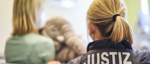 Eine Justizbeamtin und eine junge Frau zeigen ein einem Kinderschutzhaus exemplarisch eine Zeugenvernehmung, die mittels Video aus einem Nebenraum in den Gerichtssaal übertragen wird. 