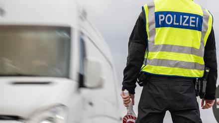27.07.2023, Brandenburg, Frankfurt (Oder): Ein Transporter passiert einen Polizisten mit Haltekelle in der Hand. An deutschen Grenzen wurden im ersten Halbjahr 2023 mehr unerlaubte Einreisen von der Bundespolizei registriert als im Jahr zuvor. 