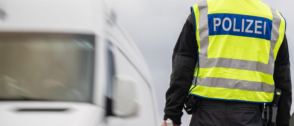 Ein Transporter passiert einen Polizisten mit Haltekelle in der Hand.