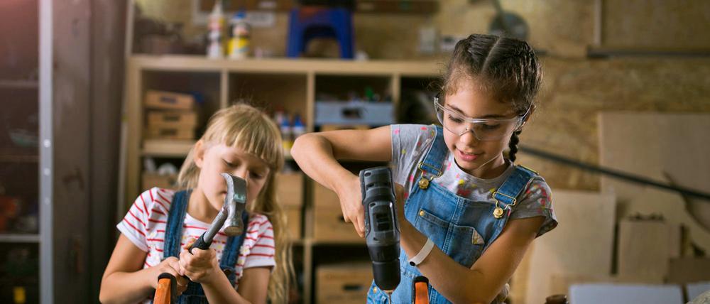 Zwei Mädchen bei Holzarbeiten in einer Werkstatt.
