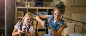 Zwei Mädchen bei Holzarbeiten in einer Werkstatt.