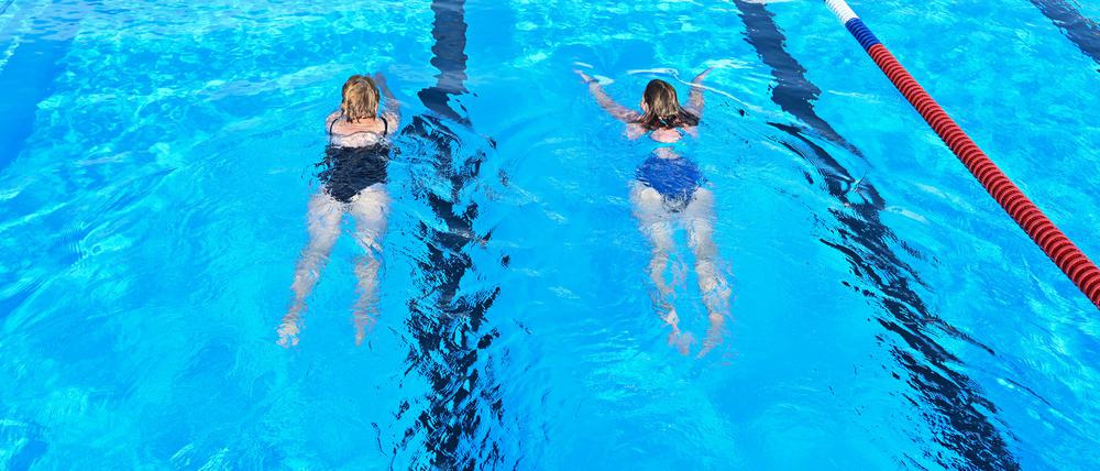 Zwei Badegäste genießen das morgige Schwimmen im Freibad.